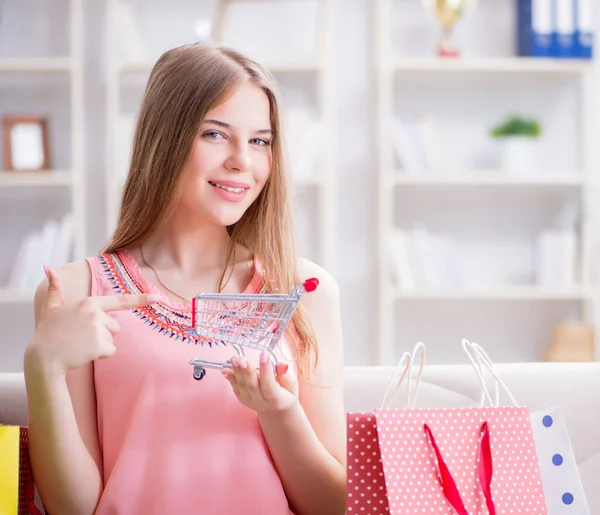 Mujer joven con bolsas de compras en el interior de casa en el sofá —  Fotos de Stock