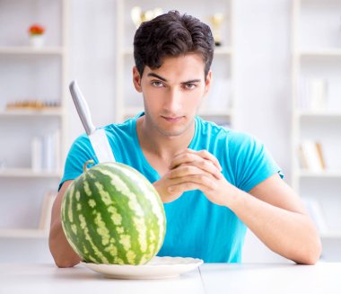 Evde karpuz yiyen bir adam.