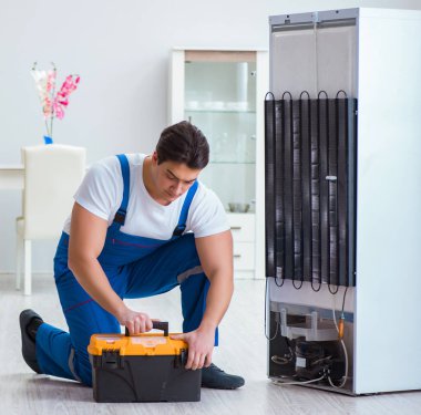 Tamirci müteahhit DIY konseptinde buzdolabını tamir ediyor.