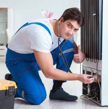 Tamirci müteahhit DIY konseptinde buzdolabını tamir ediyor.