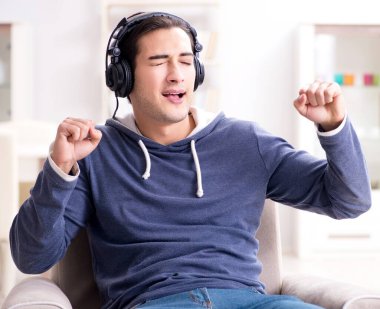 Genç adam evde müzik dinliyor.