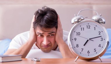 Yataktaki adam alarm yüzünden uykusuzluk çekiyor.