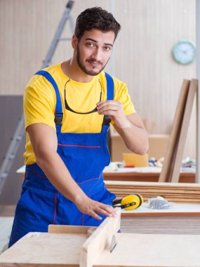 Genç bir marangoz dairesel testereyle odun kesiyor.