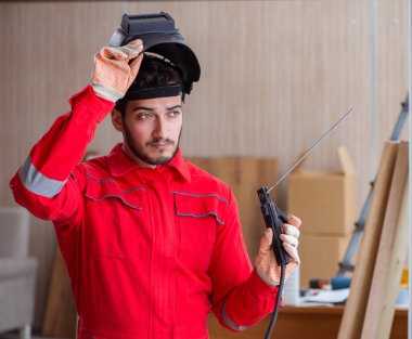 Kaynak tabancası elektrot ve kask takan genç bir tamirci.