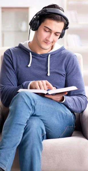 Genç adam kitap okuyor ve sesli kitap dinliyor. — Stok fotoğraf