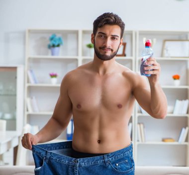 Kilo verme konseptinde büyük beden pantolon giyen bir adam.