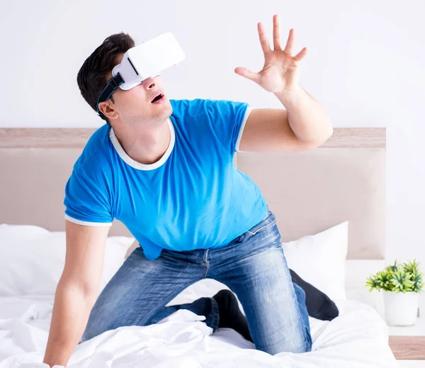 Jovem na cama vestindo um vr realidade virtual head set — Fotografia de Stock