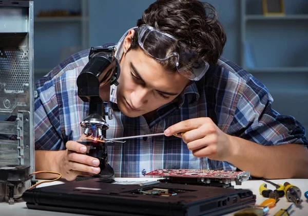 O reparador tentando reparar laptop com miscroscope — Fotografia de Stock