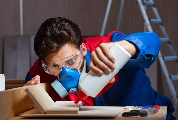 Der junge Mann klebt Holzteile in diy Konzept zusammen — Stockfoto