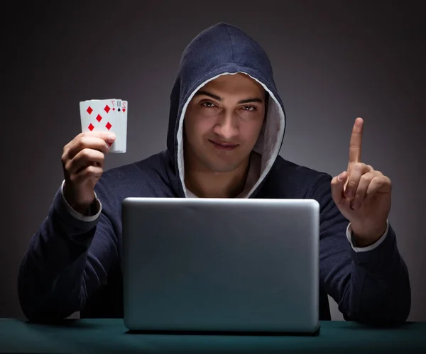 Joven con una sudadera con capucha sentado frente a una computadora portátil — Foto de Stock