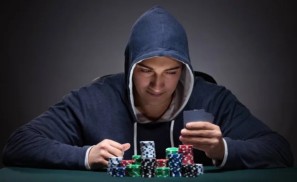 Joven con una sudadera con capucha con tarjetas y fichas de juego — Foto de Stock