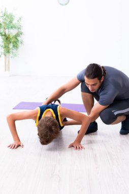 Genç baba ve oğlu egzersiz yapıyor.