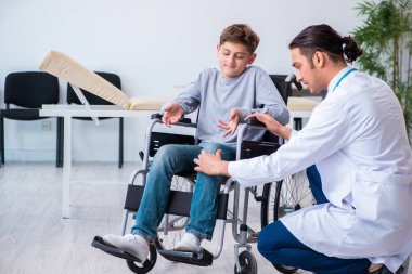 Genç erkek doktor pediatrist ve tekerlekli sandalyedeki çocuk.