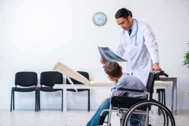 Genç erkek doktor pediatrist ve tekerlekli sandalyedeki çocuk.