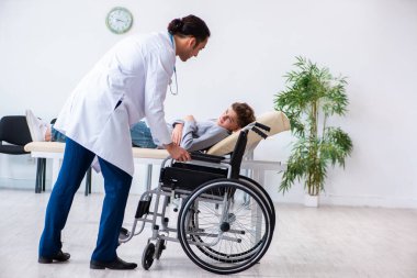 Genç erkek doktor pediatrist ve tekerlekli sandalyedeki çocuk.