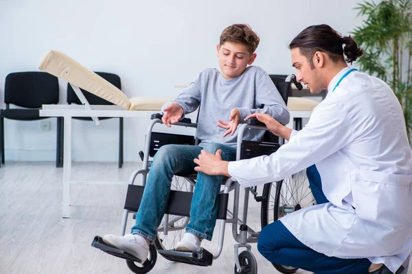 Jovem médico pediatra e menino em cadeira de rodas — Fotografia de Stock