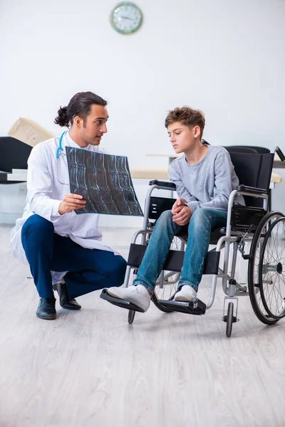 Joven doctor pediatra y niño en silla de ruedas — Foto de Stock