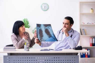 Genç doktor yaşlı yaşlı kadını muayene ediyor.