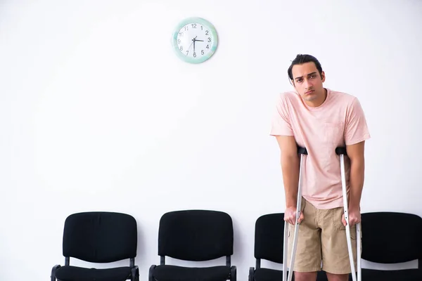 Mladý zraněný muž čeká, až bude na řadě v nemocniční hale — Stock fotografie