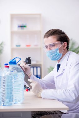 Genç erkek kimyager laboratuarda deney yapıyor.