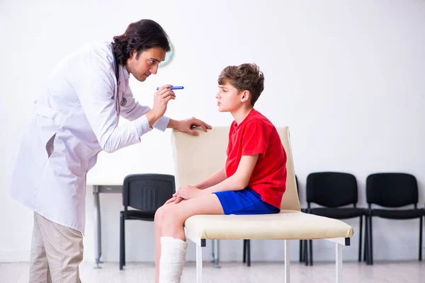 Muchacho lesionado de pierna visitando al joven médico traumatólogo — Foto de Stock