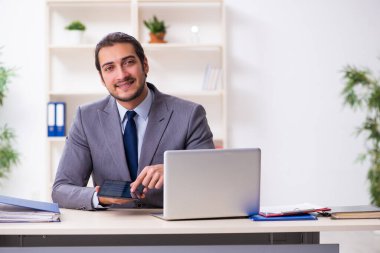 Genç işadamı ofiste oturuyor.