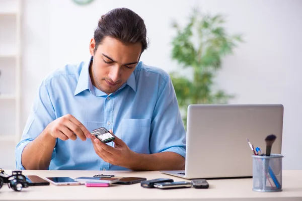 Young male technician repairing mobile phone