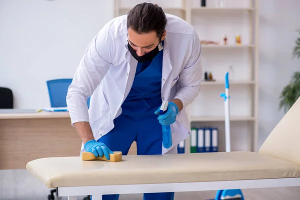 Giovane appaltatore maschile disinfezione clinica nel concetto di pandemia — Foto Stock