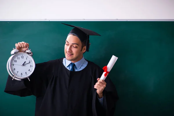 Jovem do sexo masculino graduado na frente da placa — Fotografia de Stock