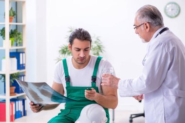 Genç erkek müteahhit yaşlı doktoru ziyaret ediyor.
