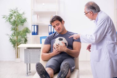 Genç yaralı futbolcu yaşlı doktor travmatoloğu ziyaret ediyor.