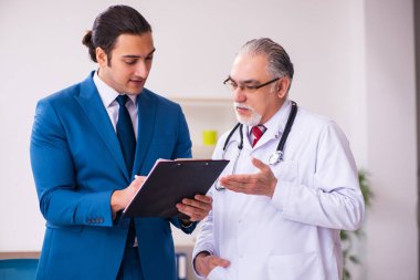 Genç işadamı yaşlı doktorla görüşüyor.