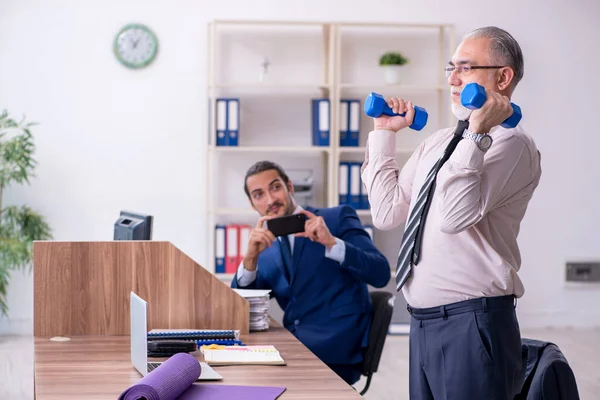 Dos empleados haciendo ejercicios físicos en el lugar de trabajo —  Fotos de Stock