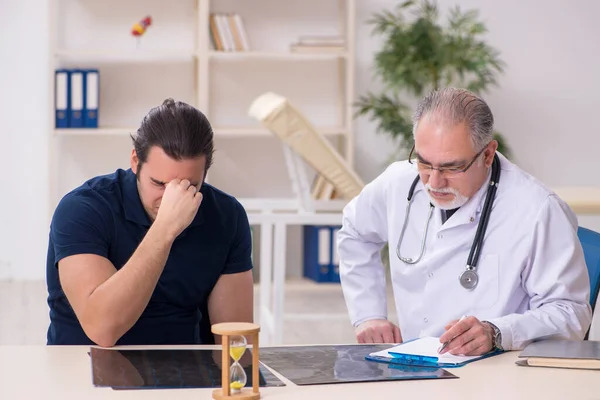 Paciente masculino joven que visita al viejo médico en el manejo del tiempo concep —  Fotos de Stock