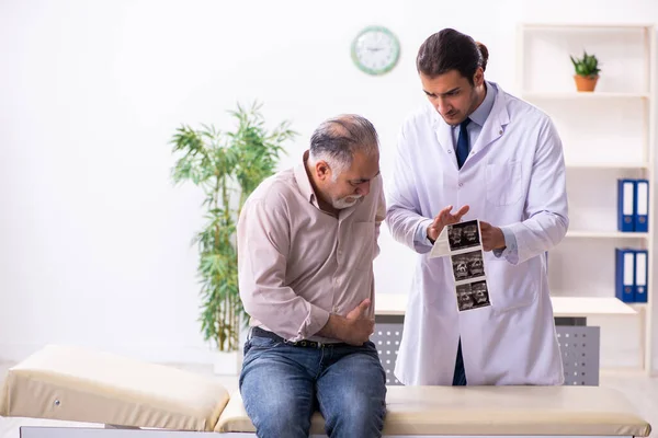 Viejo paciente visitando joven médico masculino — Foto de Stock