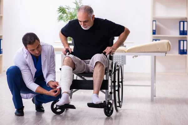 Stary ranny mężczyzna odwiedza młodego lekarza traumatologa — Zdjęcie stockowe