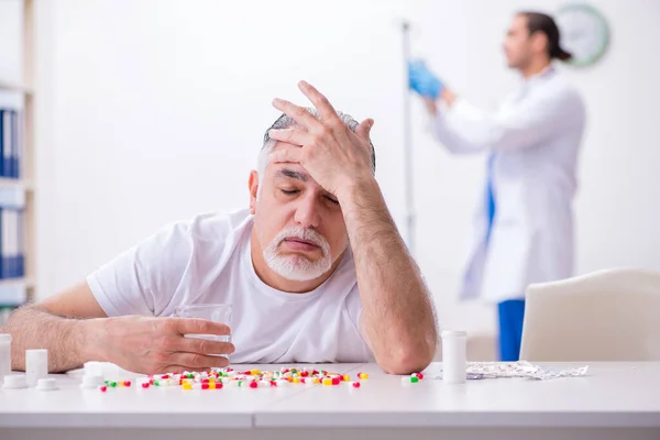 Young male doctor visiting old male patient at home — Stock Photo, Image