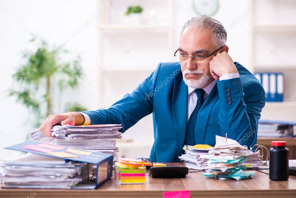 Old employee working in the office in conflicting priorities