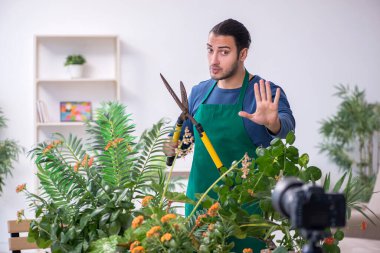 Evin içinde bitkileri olan genç bir erkek bahçıvan.