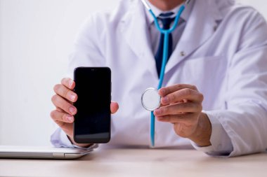 Steteskopu tamir eden genç bir erkek doktor.