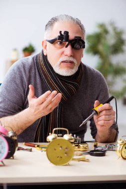 Atölyede çalışan yaşlı bir erkek saatçi.