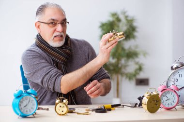 Atölyede çalışan yaşlı bir erkek saatçi.