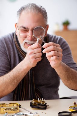 Atölyede çalışan yaşlı bir erkek saatçi.