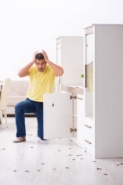 Genç adam ve evde bir sürü hamamböceği var.