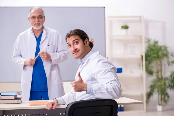 Médico experiente ensinando jovem assistente masculino — Fotografia de Stock