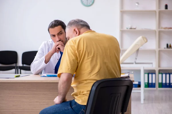 Old patient visiting young male doctor — Stock Photo, Image