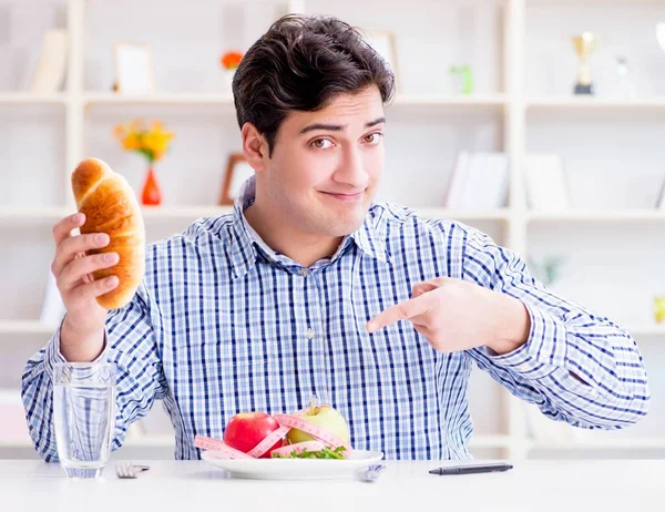 O homem tendo dilema entre alimentos saudáveis e pão na dieta con — Fotografia de Stock