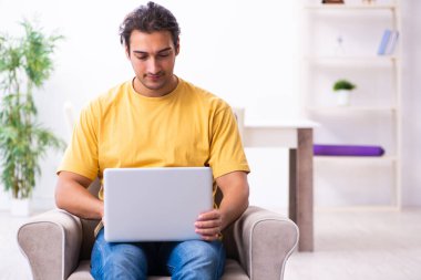 Evde bilgisayarı olan genç ve yakışıklı bir adam.