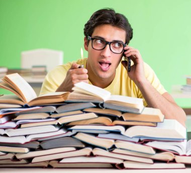 Sınavdan önce okumak için çok fazla kitabı olan öğrenci