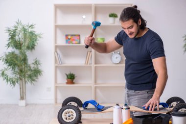 Kaykay tamir eden genç bir erkek tamirci.